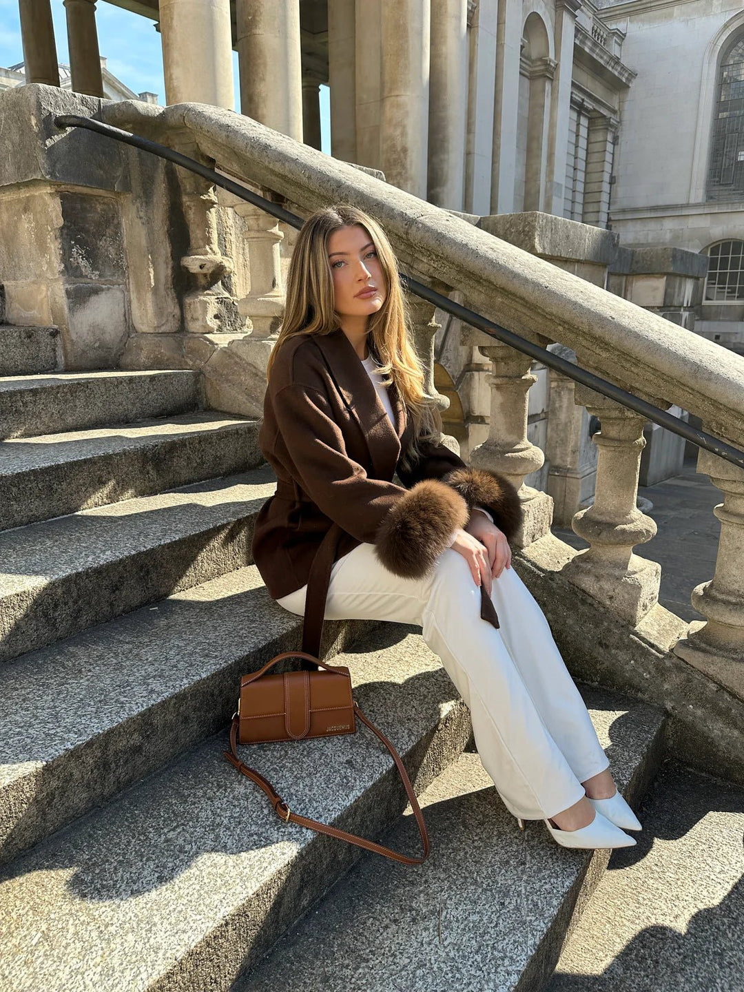 ARCTIC GRACE – Eleganter Wollmantel für Damen, kombiniert mit eleganten weißen Hosen und Accessoires.