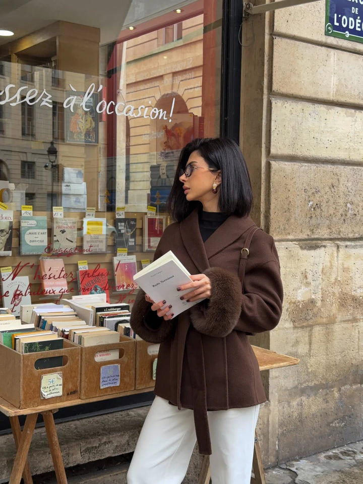 ARCTIC GRACE – Eleganter Wollmantel für Damen in elegantem Stadtsetting mit Vintage-Bücherständer.