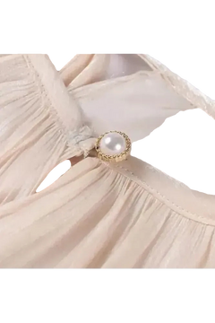 Detailansicht des Éloïse Plissee Kleids mit elegantem Knopf und plissiertem Stoff.