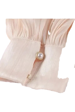 Detailaufnahme des Éloïse Plissee Kleids mit elegantem Plisseestoff und Perlenknopf.