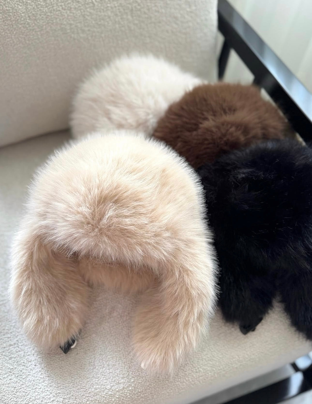 ISABELLE - Elegant Beanie in beige, brown, and black displayed on a chair, showcasing luxurious style and comfort.