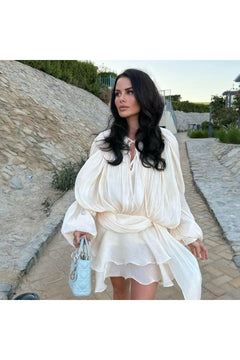 Model wearing Éloïse Plissee Kleid, showcasing elegant style with intricate design details on a stylish path.