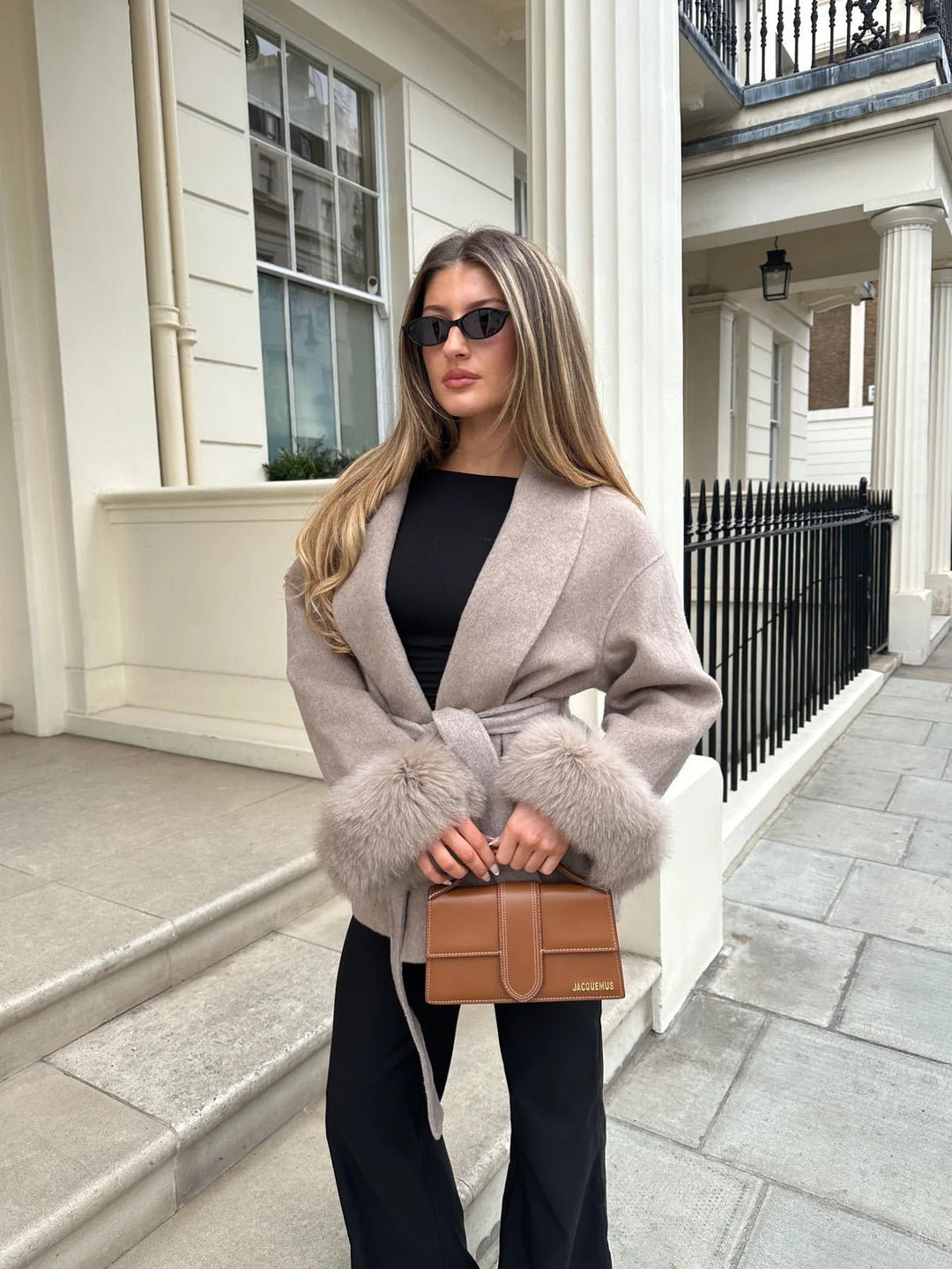 ARCTIC GRACE – Eleganter Wollmantel für Damen getragen von einem Model mit Tasche und Sonnenbrille