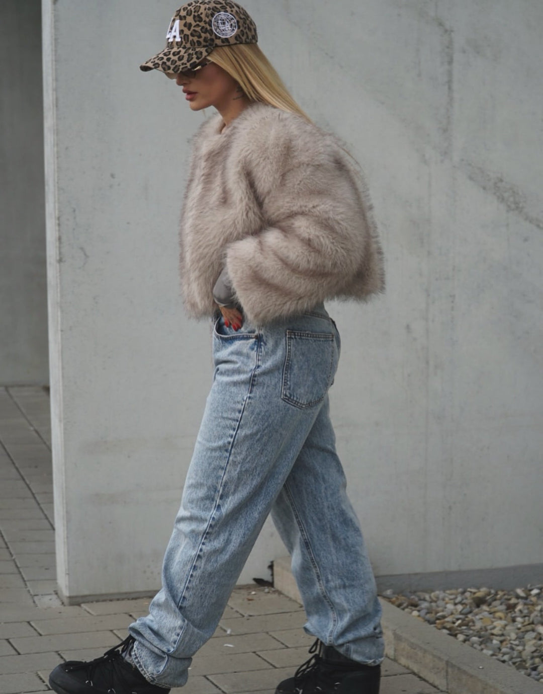 DIVINE – Luxuriöse Kunstpelzjacke mit Eleganzfaktor, kombiniert mit Jeans und einer modischen Kappe.