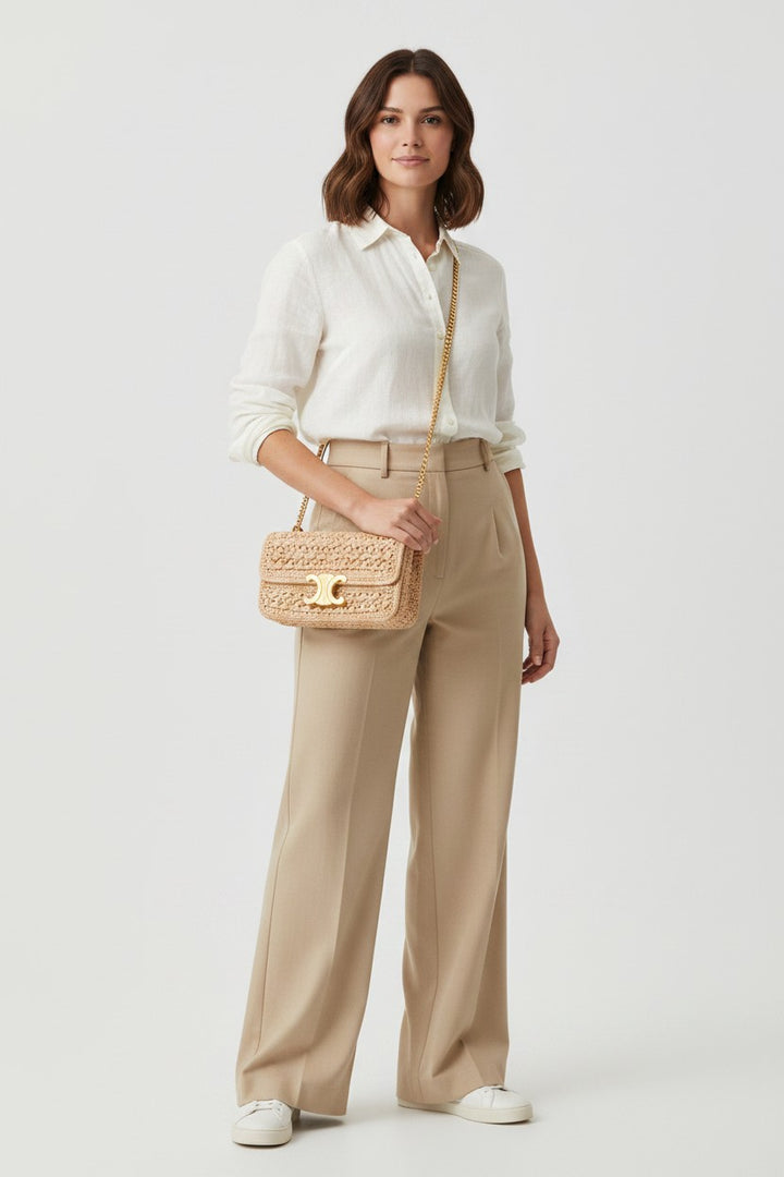 Miraee Paris Madeleine Classique Bag in woven straw with gold hardware and chain strap. Model wears beige trousers and white shirt.