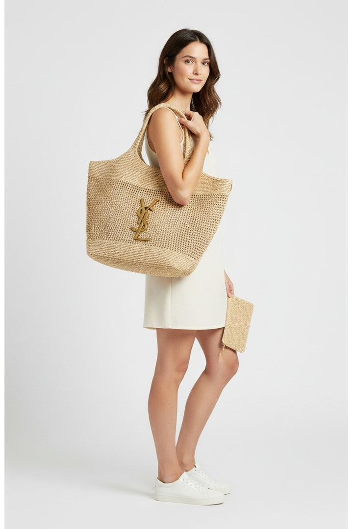 Miraee Paris Sophie tote bag in natural raffia with gold YSL logo, worn by a model in a white dress.