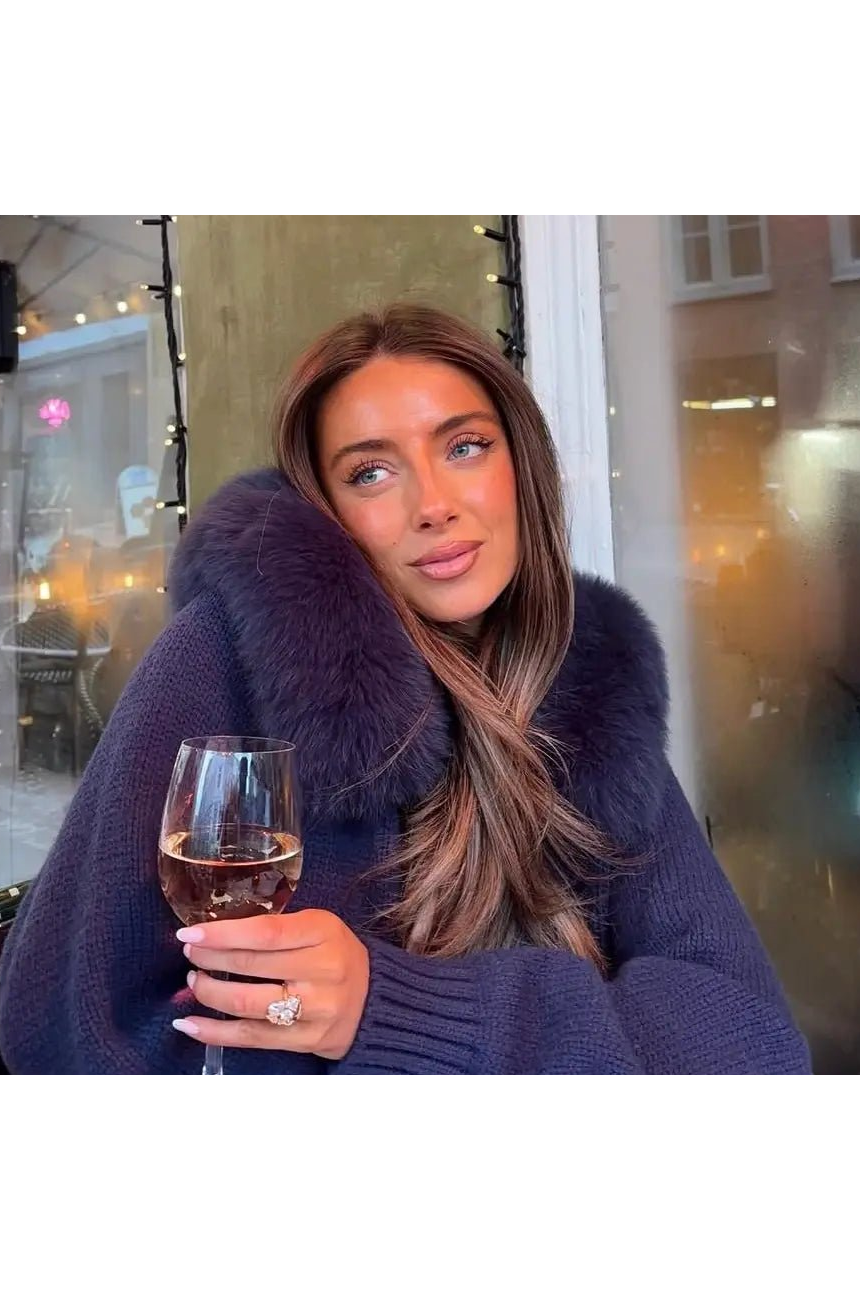 BELAMY – Chaleur Kapuzenpullover mit Fellbesatz getragen von einer Frau mit einem Glas Wein.
