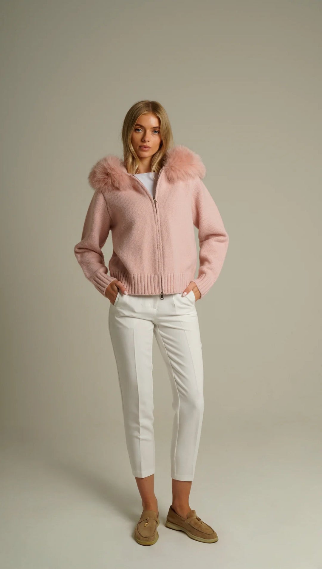 BELAMY – Chaleur Kapuzenpullover mit Fellbesatz in Rosa, kombiniert mit eleganter weißer Hose.