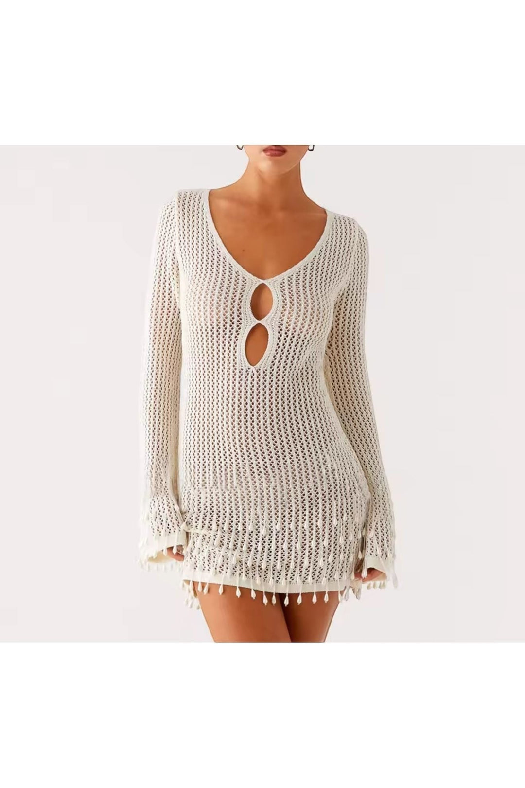 Miraee Paris white crochet beach cover-up with long sleeves, V-neckline, and tassel hem details on a model.