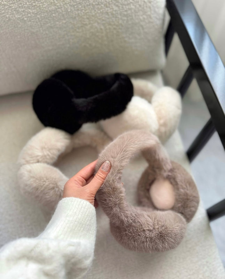 SOLEIL - flauschige Kunstpelz Ohrenwärmer in verschiedenen Farben auf einem gemütlichen Sessel.