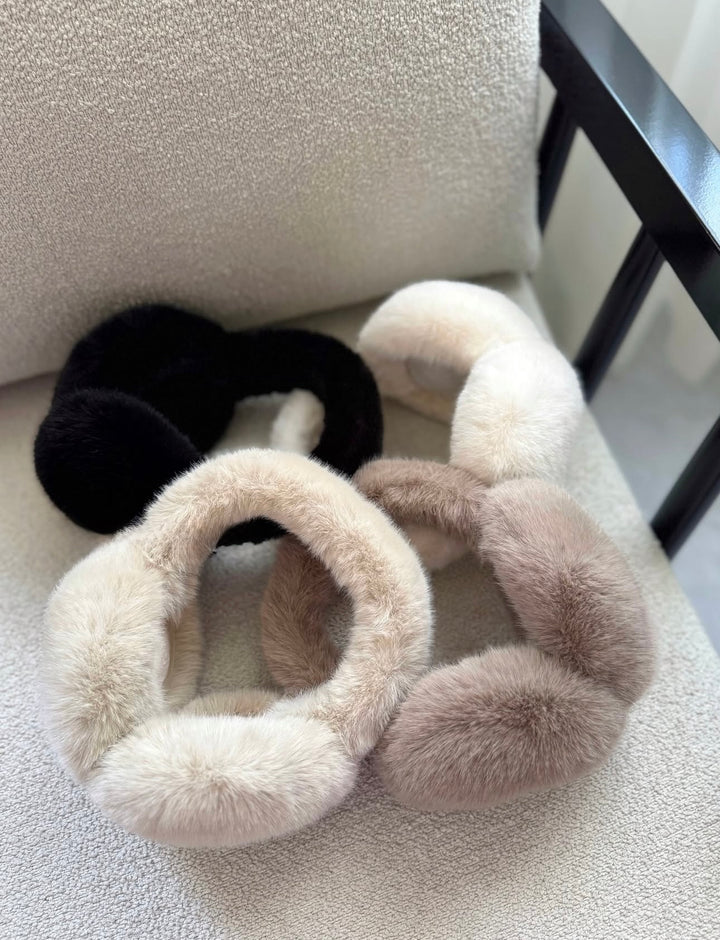 SOLEIL - flauschige Kunstpelz Ohrenwärmer in schwarz, creme und beige auf einem hellen Untergrund.